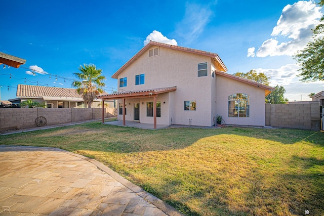 back of property with a yard and a patio