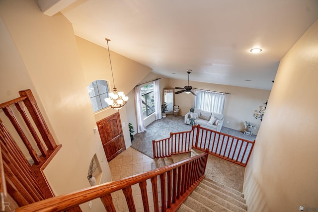 staircase featuring lofted ceiling, ceiling fan with notable chandelier, and carpet flooring