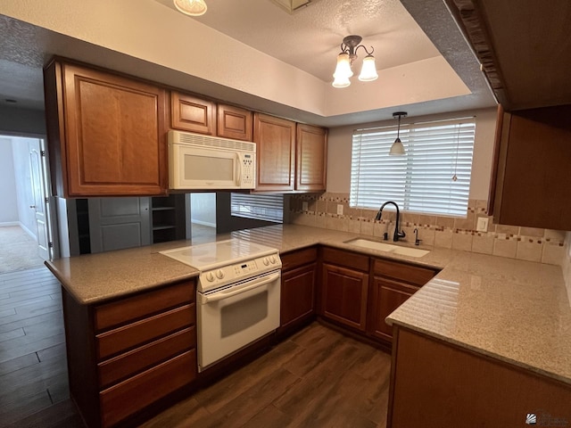 kitchen featuring dark hardwood / wood-style flooring, white appliances, pendant lighting, and sink