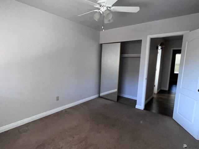 unfurnished bedroom with ceiling fan, a closet, and dark carpet