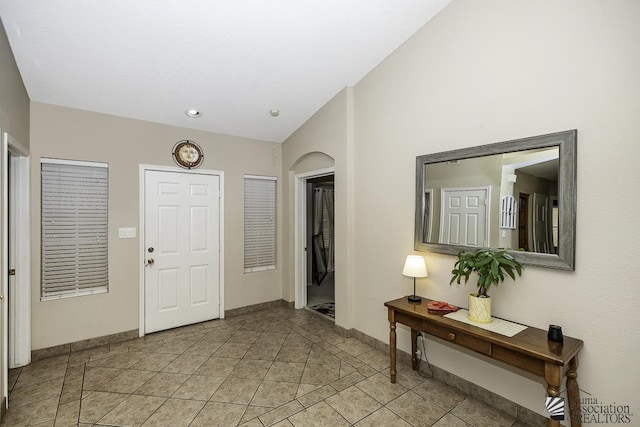 entryway with lofted ceiling, baseboards, and light tile patterned flooring