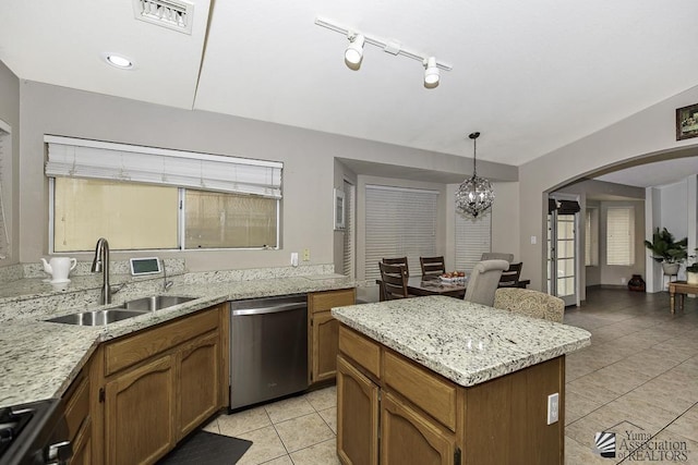 kitchen with arched walkways, a center island, visible vents, appliances with stainless steel finishes, and a sink