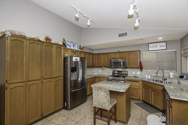 kitchen with a sink, visible vents, vaulted ceiling, appliances with stainless steel finishes, and brown cabinetry