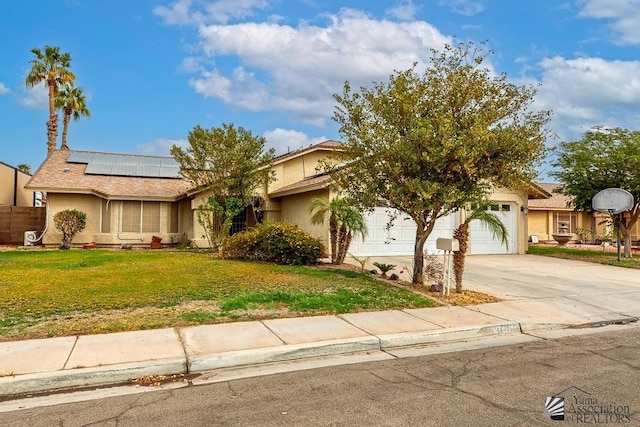 view of front of property with stucco siding, a front lawn, solar panels, and concrete driveway