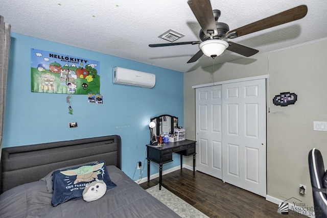 bedroom featuring visible vents, wood finished floors, a textured ceiling, an AC wall unit, and a closet