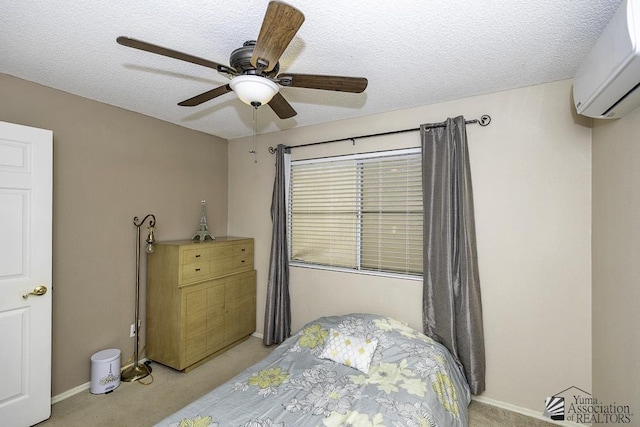 bedroom with a textured ceiling, ceiling fan, a wall mounted air conditioner, and light colored carpet