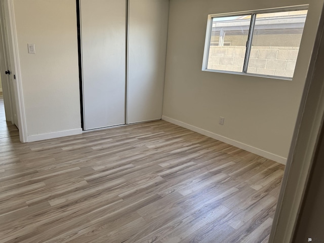 unfurnished bedroom featuring light hardwood / wood-style flooring and a closet