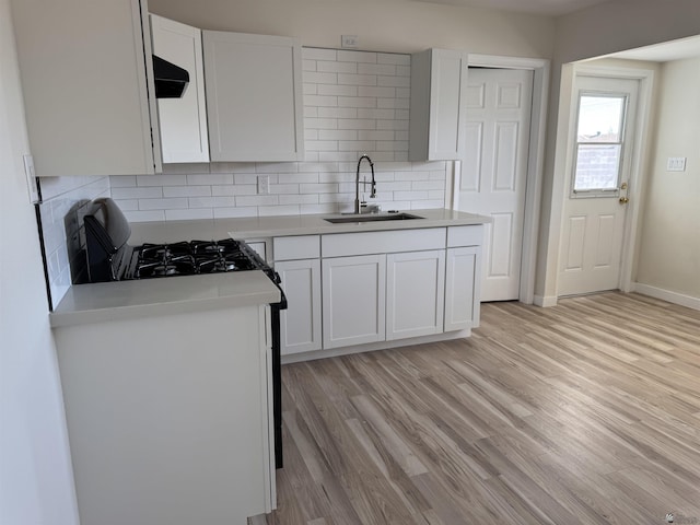 kitchen with backsplash, light hardwood / wood-style floors, sink, and white cabinets