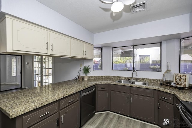 kitchen featuring dark brown cabinetry, a sink, visible vents, dishwasher, and light wood finished floors