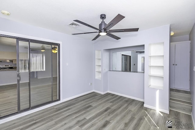 unfurnished room with baseboards, visible vents, ceiling fan, and wood finished floors