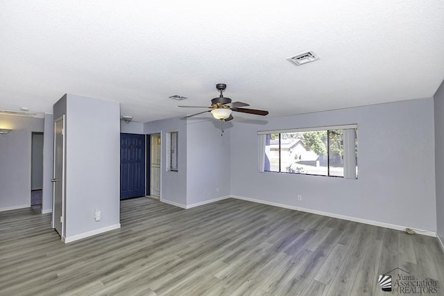 spare room with visible vents, a textured ceiling, baseboards, and wood finished floors