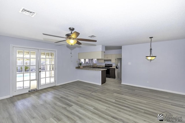 unfurnished living room with french doors, wood finished floors, visible vents, and baseboards