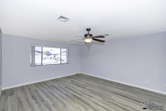 empty room with light wood finished floors, baseboards, visible vents, a ceiling fan, and a textured ceiling