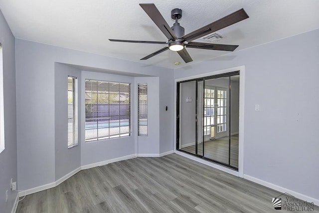 unfurnished room featuring a ceiling fan, baseboards, visible vents, and light wood finished floors