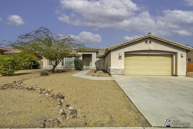 mediterranean / spanish home with a garage, driveway, stone siding, a tiled roof, and stucco siding