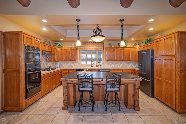 kitchen with hanging light fixtures, high quality fridge, a raised ceiling, and a kitchen island