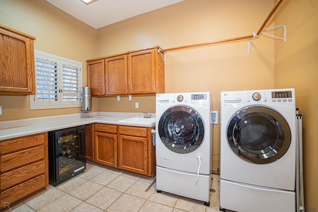 washroom featuring sink, beverage cooler, cabinets, light tile patterned floors, and independent washer and dryer