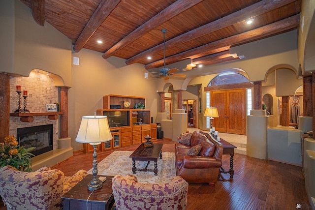 living room with beamed ceiling, wooden ceiling, hardwood / wood-style flooring, ceiling fan, and decorative columns