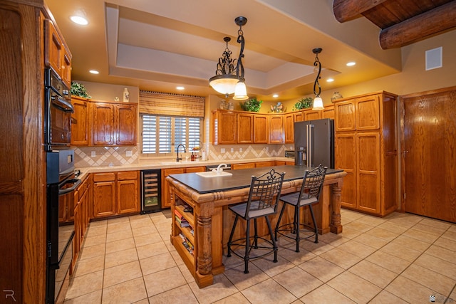 kitchen featuring wine cooler, high quality fridge, a raised ceiling, and a kitchen island