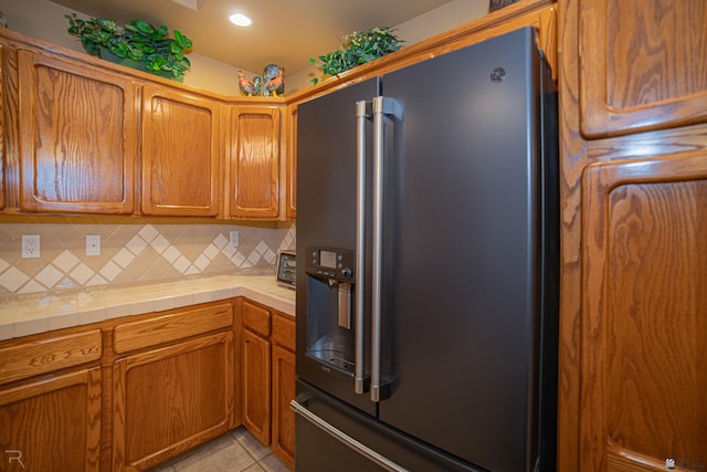 kitchen with high end fridge, tile countertops, backsplash, and light tile patterned floors