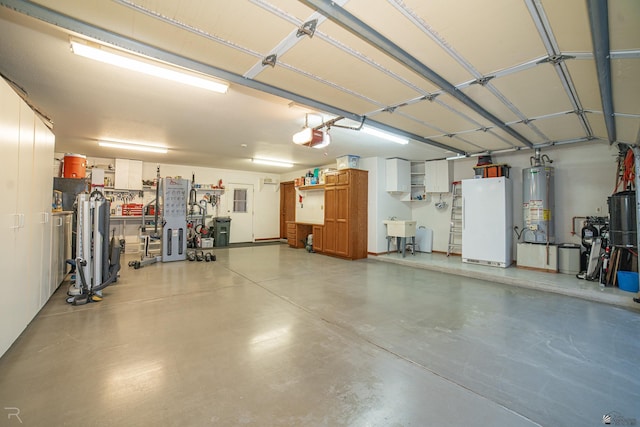 garage with a garage door opener, sink, water heater, and white fridge