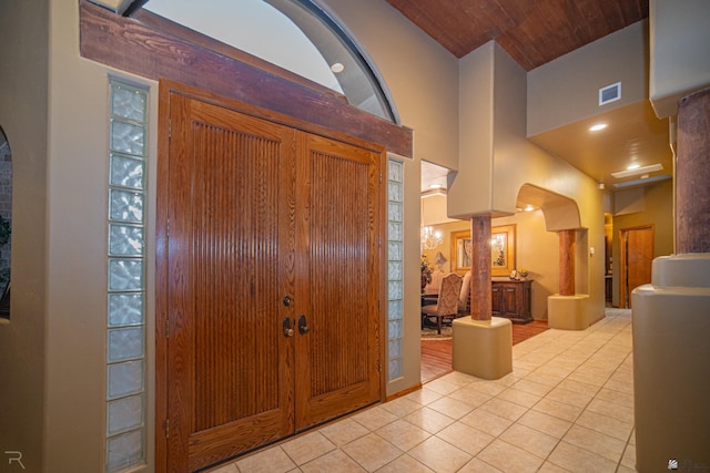 entrance foyer with wood ceiling, a towering ceiling, and light tile patterned floors