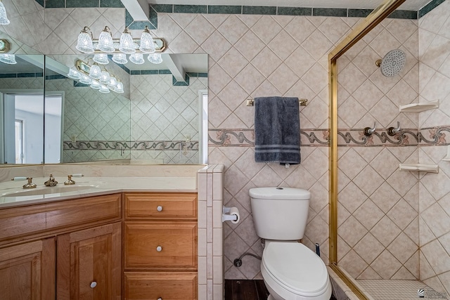 bathroom with vanity, toilet, a shower with door, and tile walls