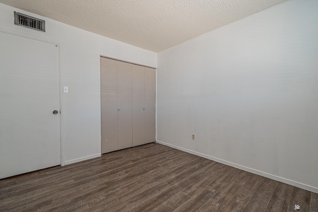 unfurnished bedroom with a closet, dark wood-type flooring, and a textured ceiling