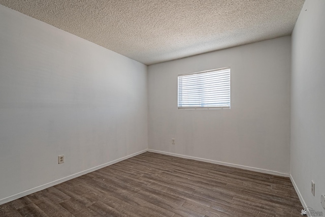 empty room with dark wood-type flooring and a textured ceiling