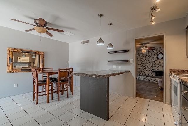 kitchen with a stone fireplace, ceiling fan, hanging light fixtures, and white appliances