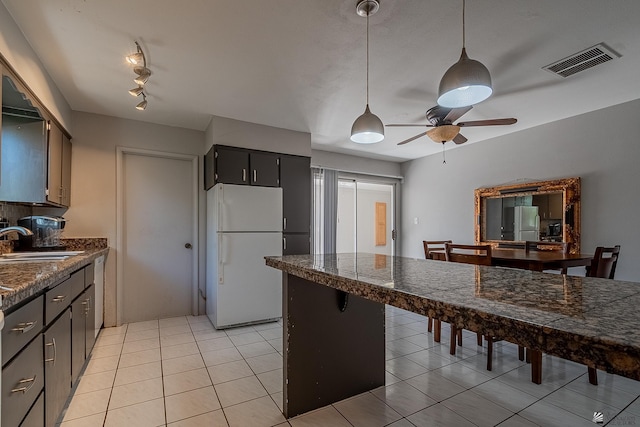 kitchen with light tile patterned floors, white refrigerator, ceiling fan, and sink