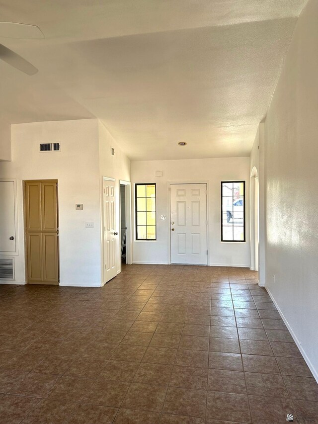 empty room with a ceiling fan, visible vents, and baseboards