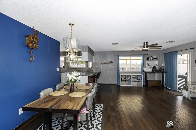 dining area with visible vents, a textured ceiling, hardwood / wood-style floors, and ceiling fan with notable chandelier