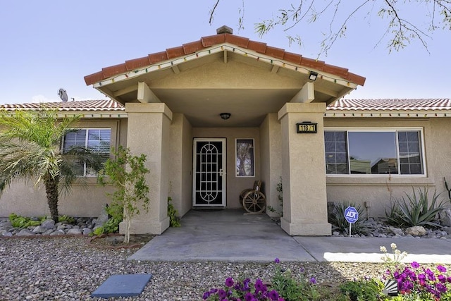 entrance to property featuring a tiled roof and stucco siding