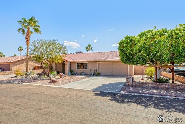 single story home with a garage, concrete driveway, a tiled roof, and stucco siding