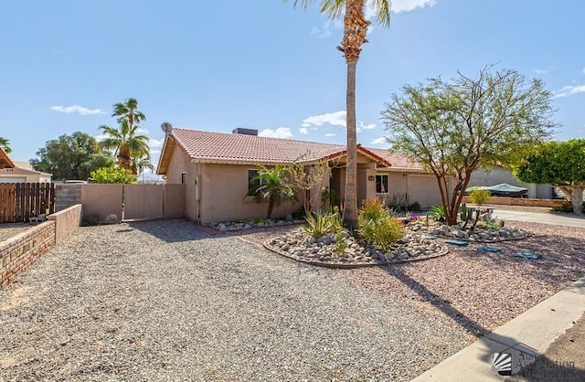 view of front of home featuring a garage, a tiled roof, a gate, fence, and stucco siding