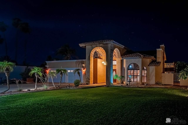 mediterranean / spanish-style house featuring a lawn and a garage