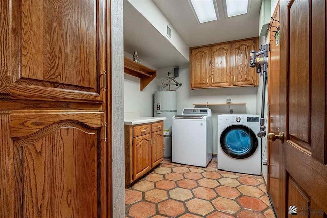 clothes washing area with strapped water heater, washing machine and dryer, and cabinets