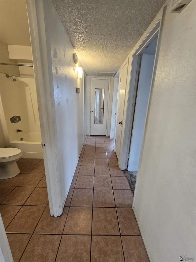 hall featuring tile patterned flooring and a textured ceiling