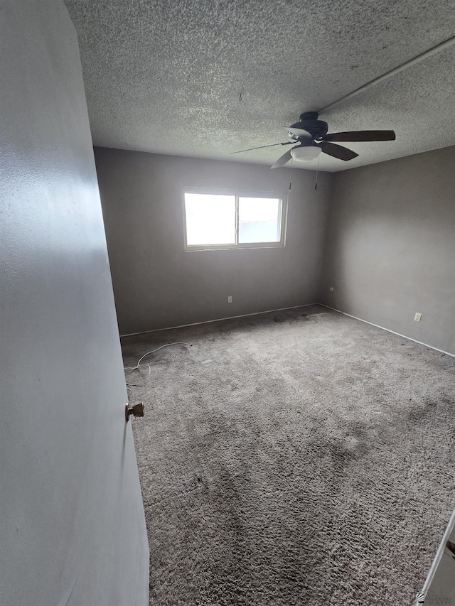 carpeted spare room featuring ceiling fan and a textured ceiling