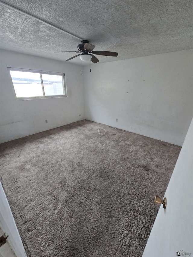 carpeted spare room with ceiling fan and a textured ceiling