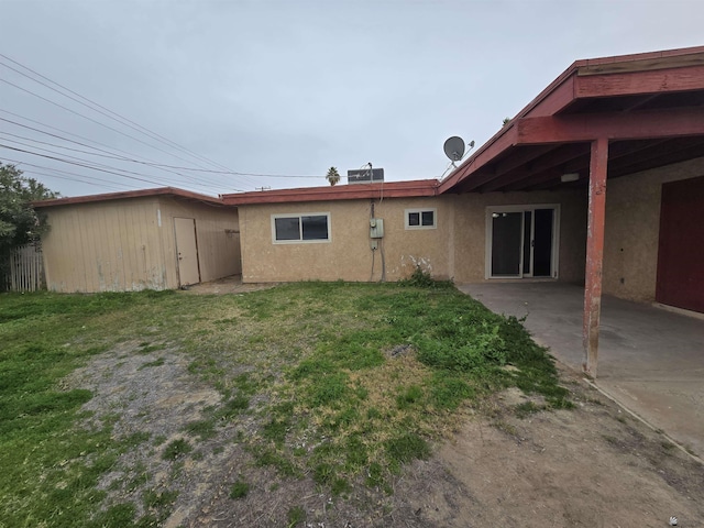 rear view of property featuring a yard, a storage unit, and a patio