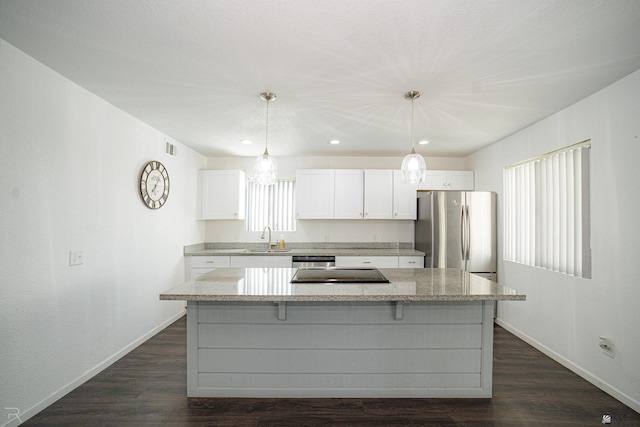 kitchen featuring stainless steel appliances, pendant lighting, white cabinetry, and a center island