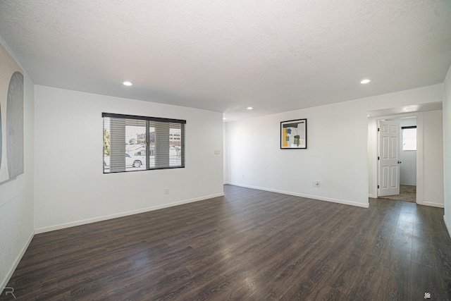 empty room featuring a textured ceiling and dark hardwood / wood-style flooring