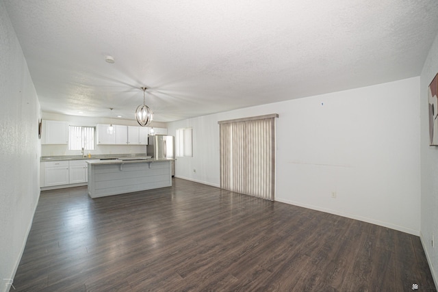 unfurnished living room featuring a textured ceiling, dark wood-type flooring, and a chandelier