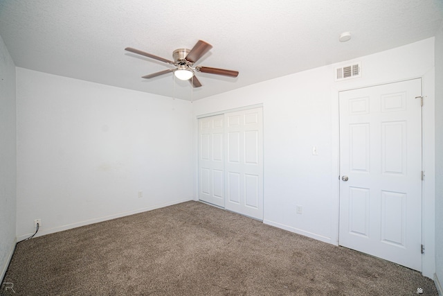 unfurnished bedroom with a textured ceiling, ceiling fan, a closet, and carpet floors