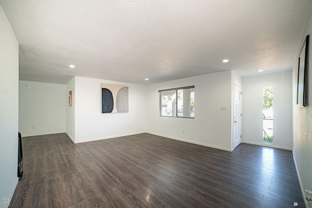 empty room with dark wood-type flooring and a textured ceiling