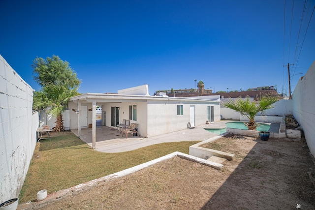 rear view of house featuring a fenced in pool, a patio area, and a lawn