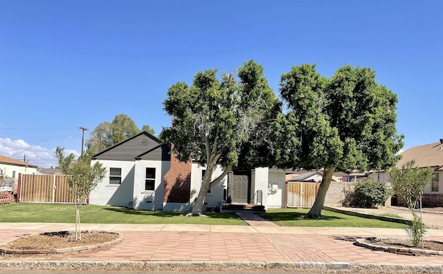 obstructed view of property with stucco siding, a front yard, and fence