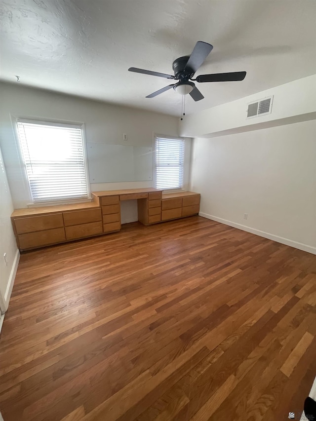 interior space with visible vents, built in study area, baseboards, and wood finished floors